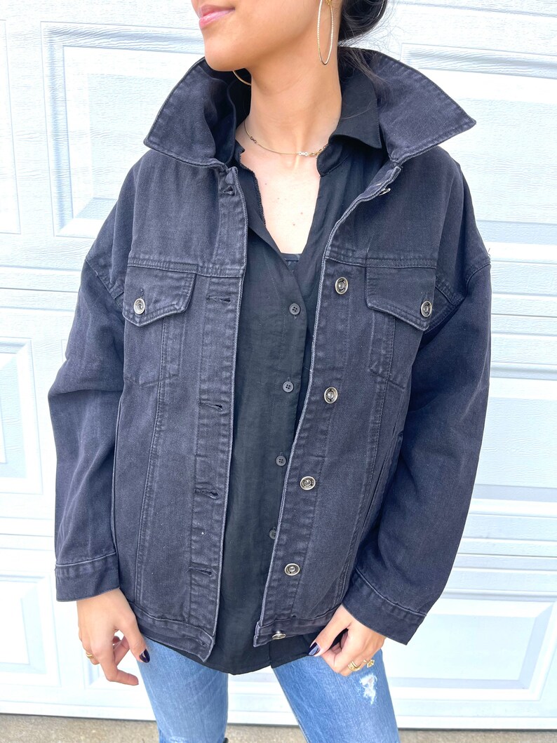 Peut inclure: Une veste en jean noire &agrave; la coupe d&eacute;contract&eacute;e et plusieurs poches. La veste se ferme par des boutons et poss&egrave;de un col classique.