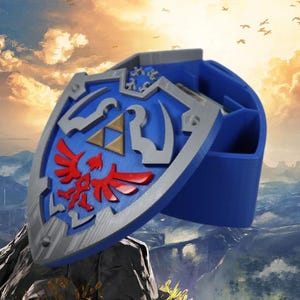 May include: A blue and silver Hylian Shield replica with a red and gold design. The shield is open and appears to be a storage container.