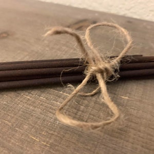 May include: A bundle of brown incense sticks tied together with twine.