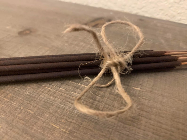 May include: A bundle of brown incense sticks tied together with twine.