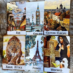 May include: A tarot card reading spread with ten cards. The cards show images of a city in Asia, a city in England, a city in Eastern Europe, a jaguar, a city in France, a cross and a woman in black, a city in Asia, a city in England, a city in Eastern Europe, and a jaguar. The cards are labelled with the following words: Asia, England, Eastern Europe, Animal Attack, France, Widowed, Asia, England, Eastern Europe, and Animal Attack.