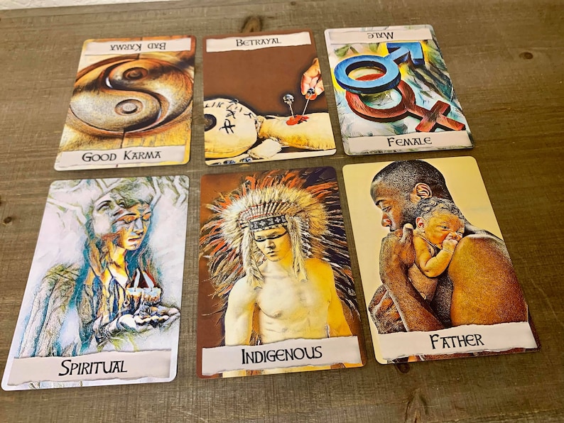 May include: Six tarot cards laid out on a wooden surface. The cards are from left to right: "Spiritual", "Indigenous", "Father", "Female", "Betrayal", and "Good Karma".
