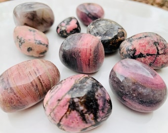 May include: A collection of nine polished pink and black tumbled stones. The stones are smooth and have a variety of patterns and textures.