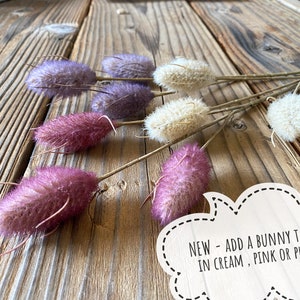 May include: A bunch of fluffy bunny tail picks in cream, pink, and purple colors. The picks are arranged on a wooden surface.  NEW - ADD A BUNNY TAIL PICK IN CREAM, PINK OR PURPLE!!!