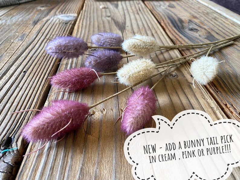 May include: A bunch of fluffy bunny tail picks in cream, pink, and purple colors. The picks are arranged on a wooden surface.  NEW - ADD A BUNNY TAIL PICK IN CREAM, PINK OR PURPLE!!!