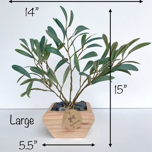 May include: A large artificial olive tree in a wooden planter with a "Handmade" tag. The tree is 15 inches tall and 14 inches wide. The planter is 5.5 inches wide.