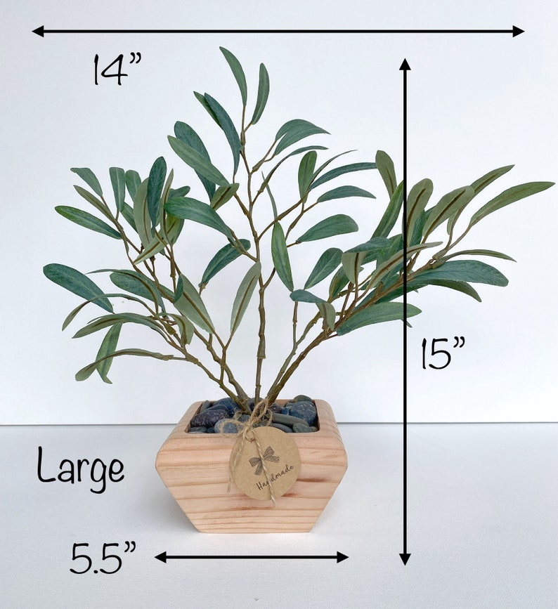 May include: A large artificial olive tree in a wooden planter with a "Handmade" tag. The tree is 15 inches tall and 14 inches wide. The planter is 5.5 inches wide.