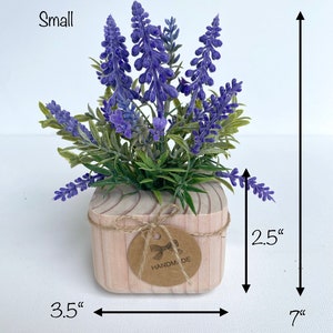 K&ouml;nnte beinhalten: Eine kleine Lavendelpflanze in einem Holztopf mit einem handgefertigten Etikett. Die Pflanze ist 17,8 cm hoch und der Topf ist 8,9 cm breit und 6,4 cm hoch.