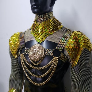Pu&ograve; includere: Set di gioielli da costume dorati con un ciondolo a testa di leone, maglie a catena e una base in tessuto a rete. Il set comprende una collana choker, un'imbracatura e due pezzi per le spalle.