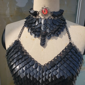 Op de afbeelding: Een zwart kettinghemd haltertop met een bijpassende choker ketting. De choker heeft een decoratief oog hanger met een rode edelsteen.