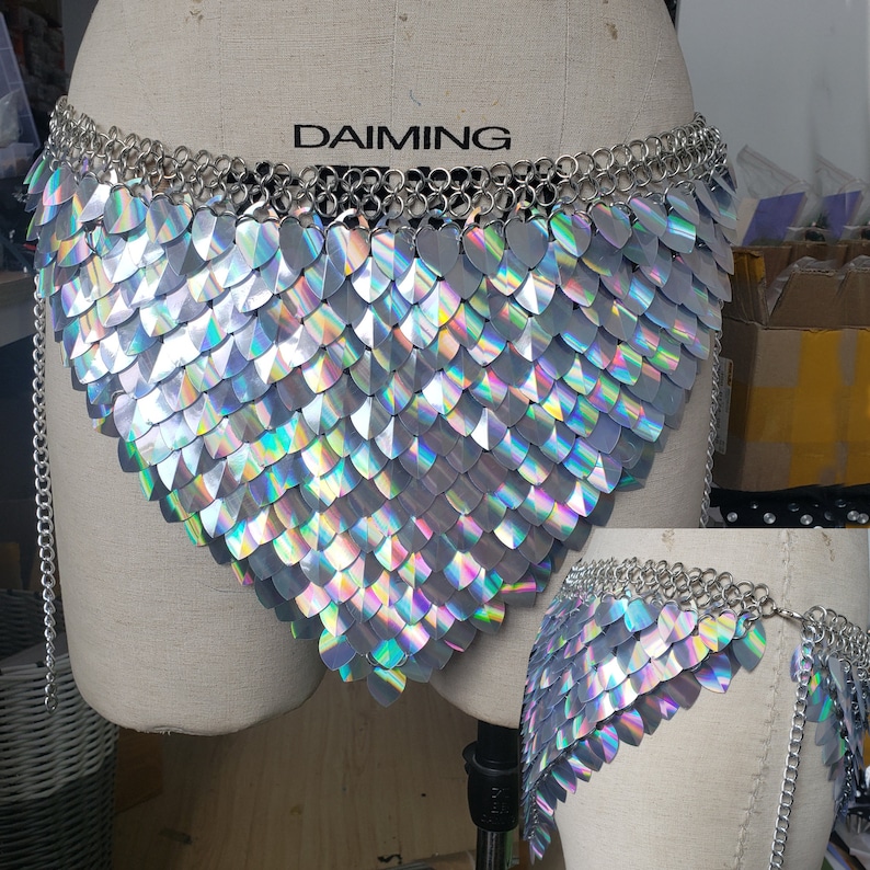 Op de afbeelding: Een zilveren kettinghemd body chain met iriserende schubben. Het kettinghemd heeft een V-vorm en heeft een DAIMING label aan de bovenkant.