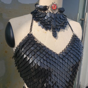 Op de afbeelding: Een zwart kettinghemd top met een bijpassende choker ketting. De choker heeft een rode oog charme.