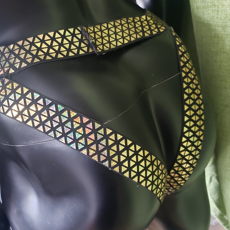 Pu&ograve; includere: Lingerie nera con motivo a triangoli dorati e fascia elastica nera.