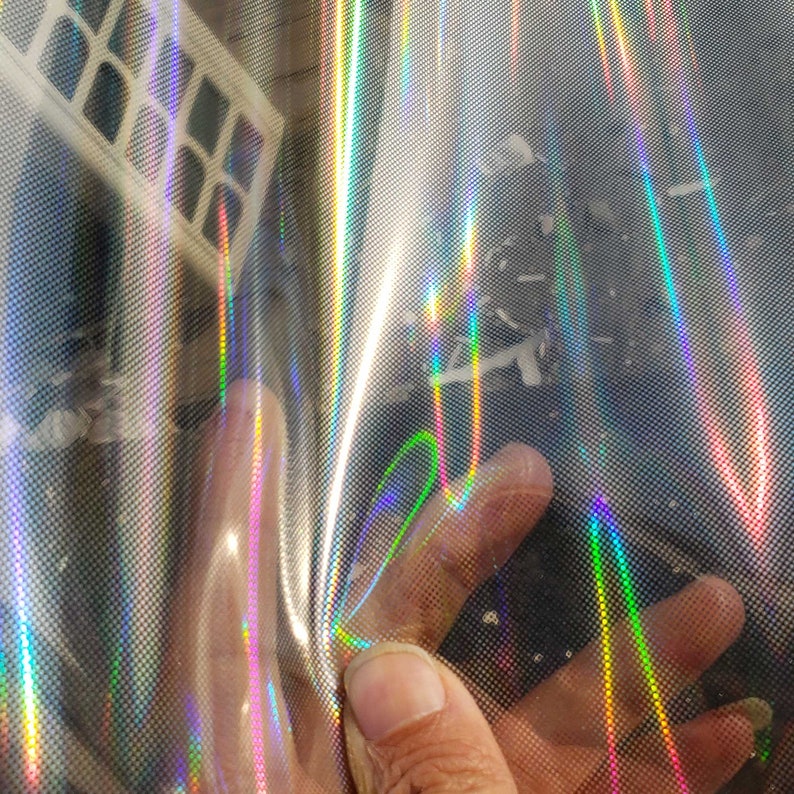 May include: A sheet of iridescent holographic vinyl with a rainbow pattern. The vinyl has a textured surface and is slightly wrinkled.
