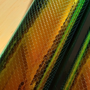May include: Two rolls of iridescent green and gold vinyl with a snake skin pattern.