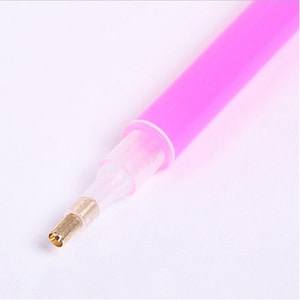 May include: A pink plastic tool with a gold metal tip for picking up and placing diamond painting drills.