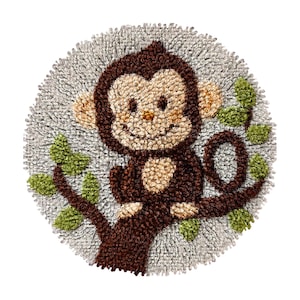 Può includere: Un tappeto rotondo, fatto a mano, con una scimmia marrone sorridente appollaiata su un ramo con foglie verdi. La scimmia ha un viso e orecchie marrone chiaro, su uno sfondo grigio strutturato.
