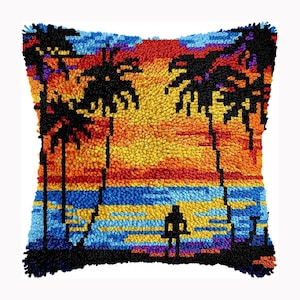 May include: A square throw pillow featuring a textured punch needle design of a sunset beach scene. The image displays black silhouettes of palm trees and a person standing on the shore against a vibrant background of orange, yellow, and blue yarn.