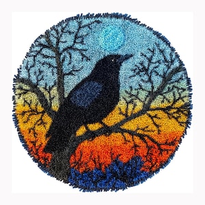 May include: A circular punch needle wall hanging featuring a black crow perched on a bare tree branch. The background displays a gradient sky transitioning from a bright blue moon at the top to orange and red hues at the bottom, with dark blue foliage.