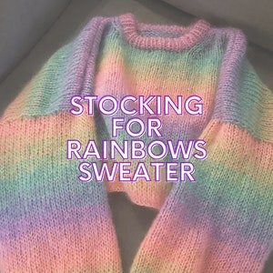 以下が含まれることがあります： 虹色のストライプのニットセーターで、前面に「STOCKING FOR RAINBOWS SWEATER」の文字が書かれています。