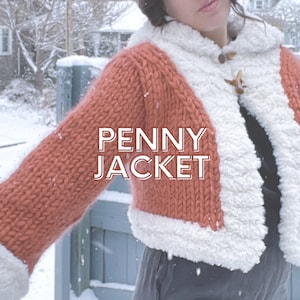 May include: A close-up of a woman wearing a knitted orange and white jacket with the text "PENNY JACKET" on the front. The jacket has a fluffy white trim around the edges.