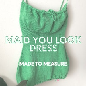 Puede incluir: Un vestido de punto verde con escote fruncido y tirantes finos. El vestido está hecho a medida y tiene el texto "Maid You Look Dress" impreso.