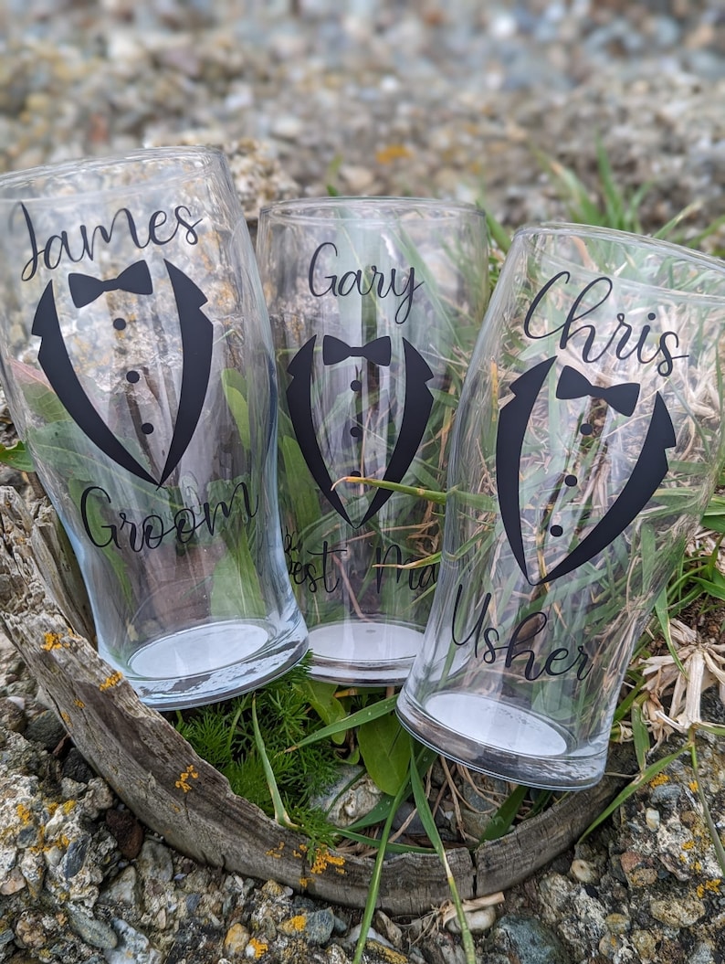 May include: Three clear glass pint glasses with black tuxedo designs and personalized names: James Groom, Gary Best Man, and Chris Usher.