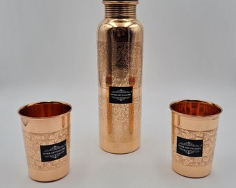 May include: A set of three copper water bottles with intricate floral designs. The bottles are engraved with the text "Vivek Art Gallery".