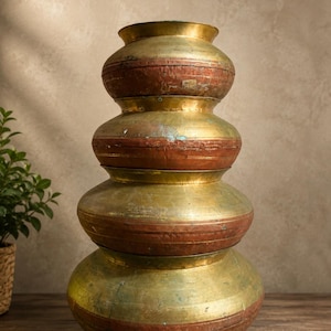 May include: A stack of four round metal pots with wide, curved bodies and narrow openings. The pots feature a two-tone design with a metallic gold finish on the upper and lower sections and a weathered, reddish-brown band around the center.