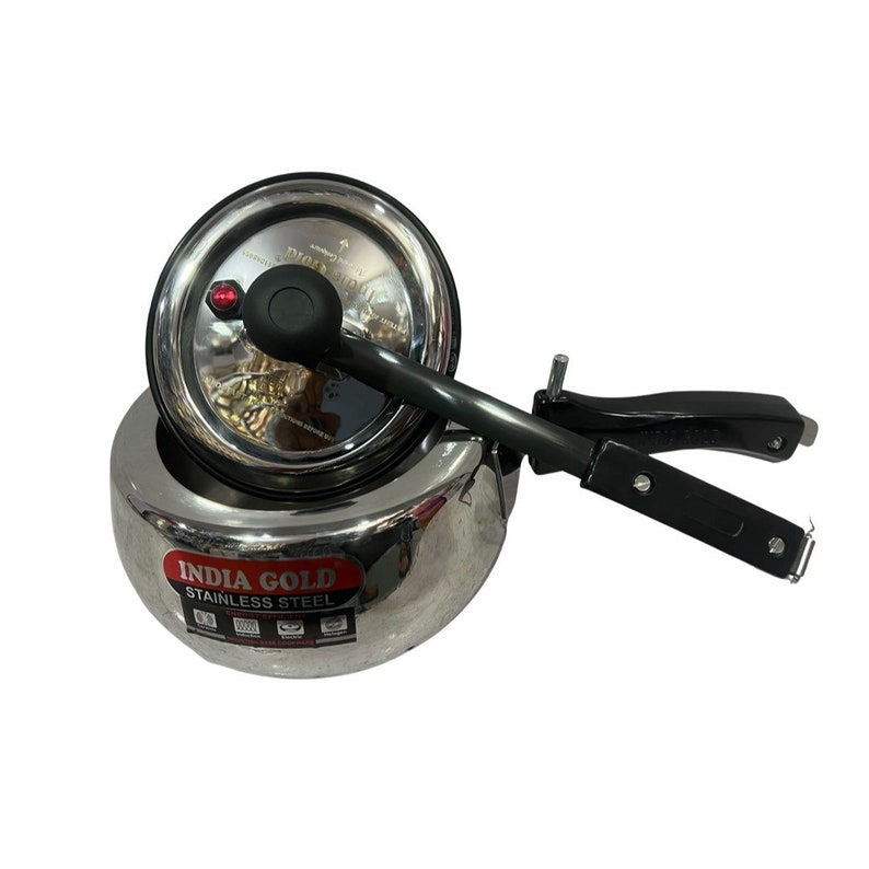 May include: A silver stainless steel pressure cooker with a black handle and a red pressure release valve. The cooker has the text "INDIA GOLD STAINLESS STEEL" printed on the side.