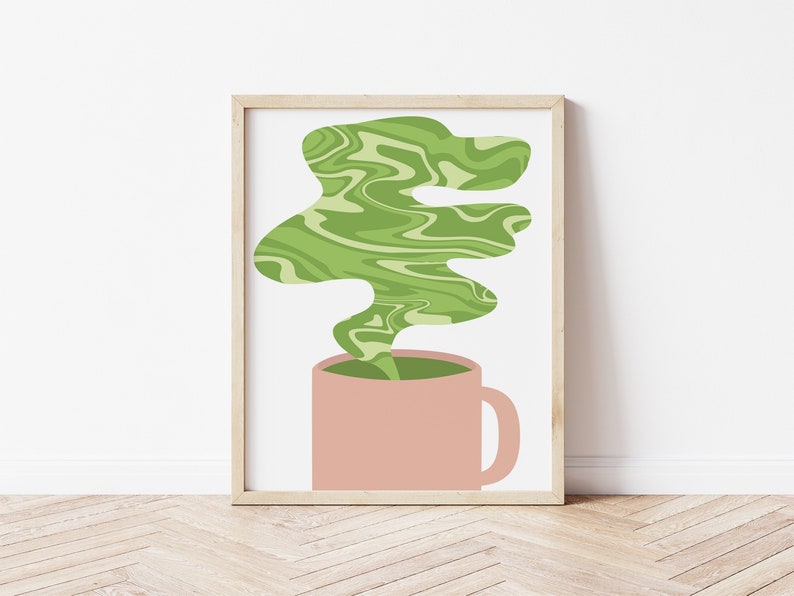 May include: A framed art print featuring a pink mug with green, swirling steam rising from it. The steam has a marbled effect, and the background is white. The frame is a light wood color, and the overall style is minimalist.