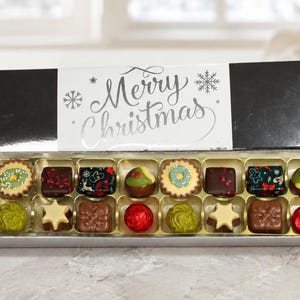 Caja de bombones de lujo con envoltorio de copo de nieve plateado con el mensaje "Feliz Navidad". 8 o 16 bombones vegetarianos belgas y suizos en caja de regalo plateada.