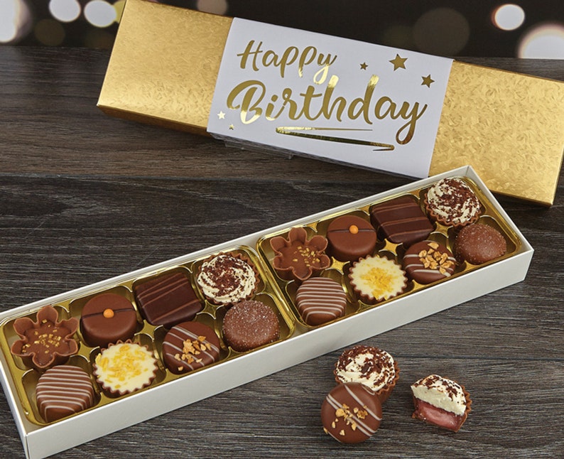 May include: A white box filled with assorted chocolates, with a gold box on top that says "Happy Birthday".
