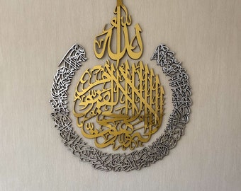 May include: A gold and silver metal wall art featuring intricate Arabic calligraphy. The design includes the word "Allah" in a large, bold font, surrounded by smaller, more delicate script.