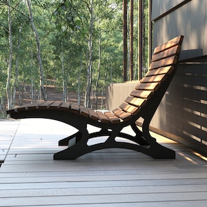 May include: A wooden slatted lounge chair with a black metal frame. The chair is on a wooden deck with a view of a forest in the background.