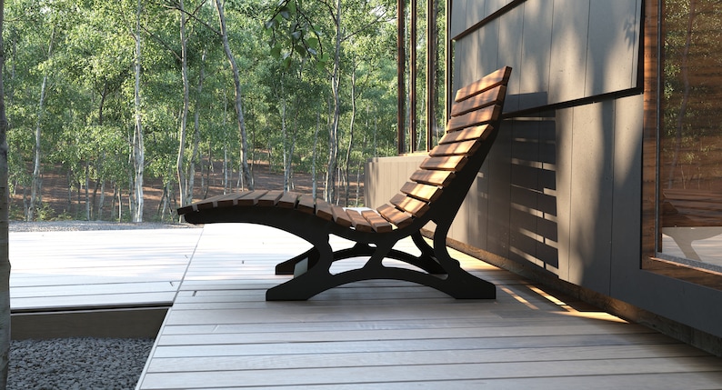 May include: A wooden slatted lounge chair with a black metal frame. The chair is on a wooden deck with a view of a forest in the background.