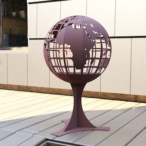 Puede incluir: Un brasero de metal en forma de globo con un acabado marrón. El globo está sobre un soporte con una base de tres puntas.