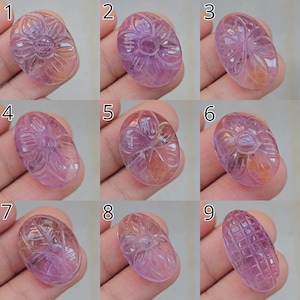 May include: Nine oval gemstones with detailed floral and geometric carvings. The stones have a colour gradient from pink to orange. Each stone is unique, showcasing detailed craftsmanship and varying designs.