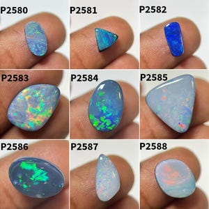 Peut inclure: Collection de neuf pierres précieuses opales de différentes formes, dont ovales, triangulaires et en goutte. Les opales présentent une gamme de couleurs, notamment le bleu, le vert et des reflets irisés. Chaque pierre est présentée sur un fond neutre.