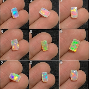 May include: Nine rectangular opal gemstones with iridescent color play are displayed. Each stone is held in a hand, showcasing the variety of colors, including blues, greens, yellows, and pinks. The opals have a polished, faceted surface.