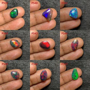 May include: Nine black opal gemstones of various shapes and sizes, including teardrop, oval, and triangular, with iridescent colors of green, blue, red, and purple. The gemstones are labeled with product numbers P539, P540, P541, P542, P543, P544, P545, P546, and P547.