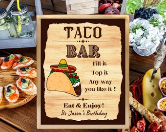May include: A wooden sign with a brown background and a light wood frame. The sign says "Taco Bar" in large letters and has a cartoon image of a taco with a sombrero on top. The text below the image says "Fill it, Top it, Any way you like it! Eat & Enjoy! It's Jason's Birthday."