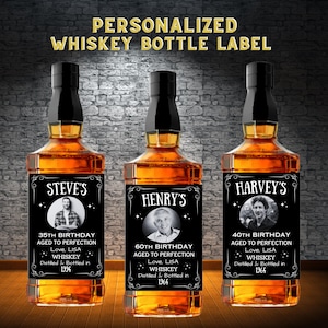 Peut inclure: Trois étiquettes de bouteille de whisky personnalisées avec un fond noir et du texte blanc. Les étiquettes présentent une photo d'une personne, le nom de la personne et un message d'anniversaire. Les étiquettes disent "Steve's 35th Birthday Aged to Perfection Love, Lisa Whiskey Distilled & Bottled in 1994", "Henry's 60th Birthday Aged to Perfection Love, Lisa Whiskey Distilled & Bottled in 1964", et "Harvey's 40th Birthday Aged to Perfection Love, Lisa Whiskey Distilled & Bottled in 1964".