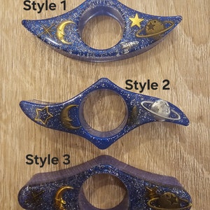 K&ouml;nnte beinhalten: Drei Lesezeichen in Blau und Silberglitter mit Weltraumthema. Jedes Lesezeichen zeigt einen Halbmond, einen Stern, eine Rakete und einen Planeten mit Ringen. Die Lesezeichen sind mit "Style 1", "Style 2" und "Style 3" beschriftet.