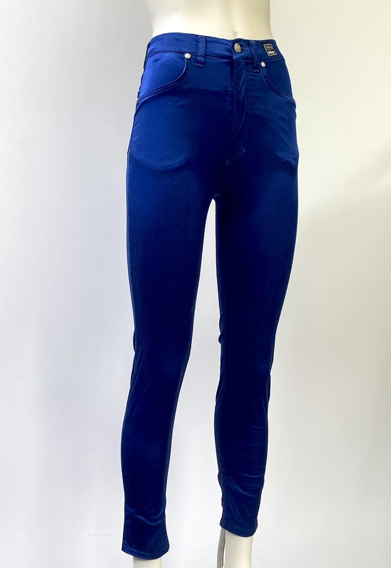May include: A pair of high-waisted, form-fitting, navy blue velvet pants. The pants have a classic five-pocket design with a button and zipper closure. The fabric has a subtle sheen, and the pants are displayed on a mannequin.