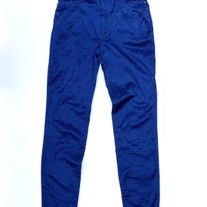May include: A pair of blue denim pants with the Versace logo on the waistband. The pants have a classic five-pocket design and a button and zipper closure. The fabric appears to be a medium-weight denim.