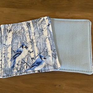 May include: Two blue bird patterned fabric coasters with a blue and white herringbone pattern on the back.