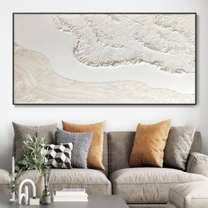 May include: A framed abstract painting with a white and cream color scheme. The painting features a textured, layered design that resembles waves or clouds.
