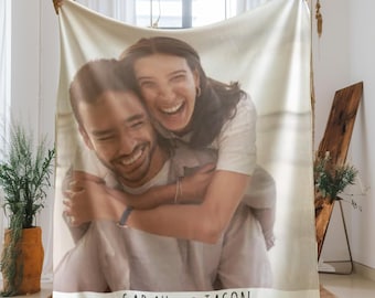 May include: A white fleece blanket with a personalized photo of a couple. The photo shows a man and a woman smiling and hugging. The text "SARAH ♥ JASON" is printed on the bottom of the blanket.