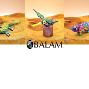 May include: Three hand-painted wooden animal figurines: a green and yellow lizard, a green hummingbird with a yellow beak, and a purple chameleon with colorful floral patterns.